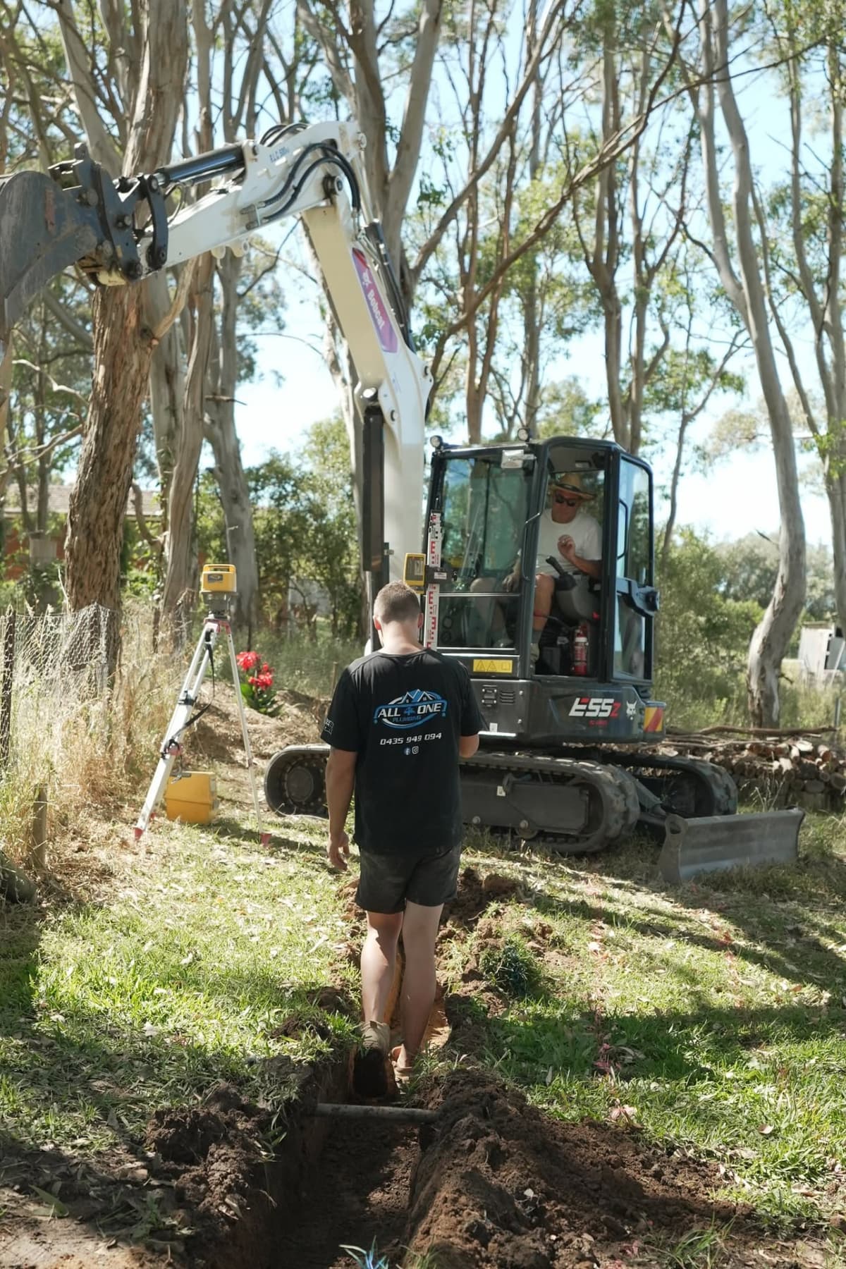 Excavator digging a new sewer line while Josh checks the trench